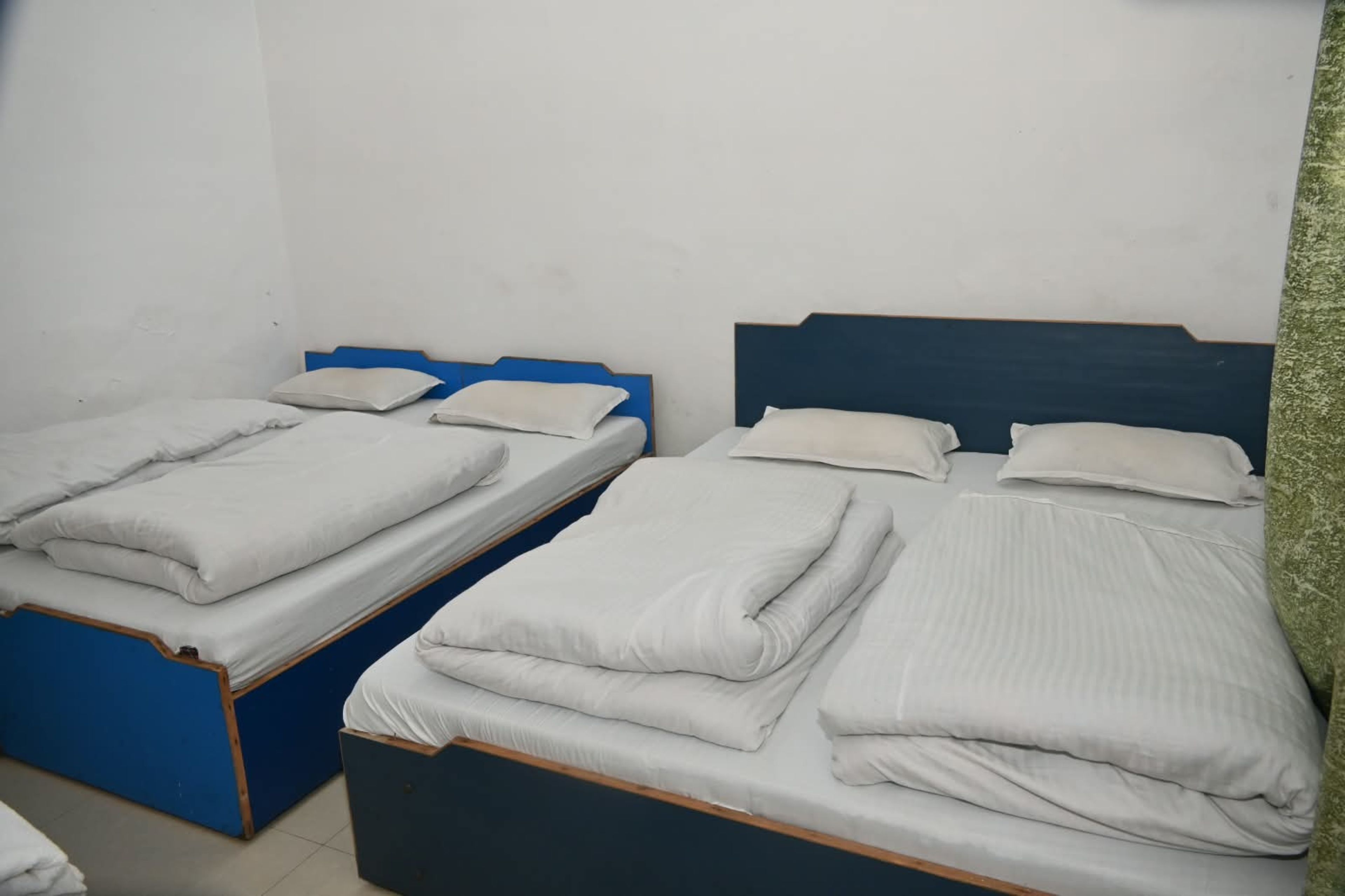 Two single beds with wooden frames and blue headboards, each with white bedding.