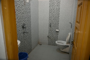 Ein Badezimmer mit Toilette, Dusche und einem blauen Eimer.