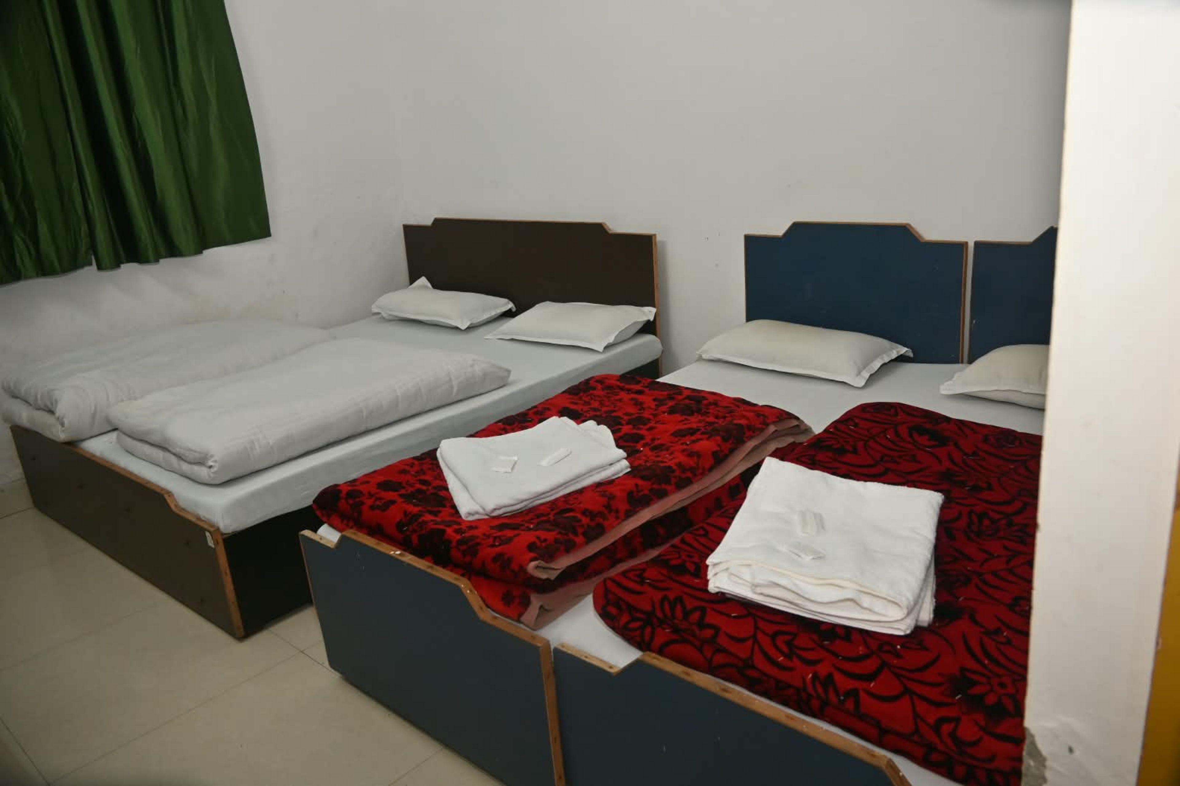 Habitación de hotel con dos camas individuales y una cama doble, todas con ropa blanca.