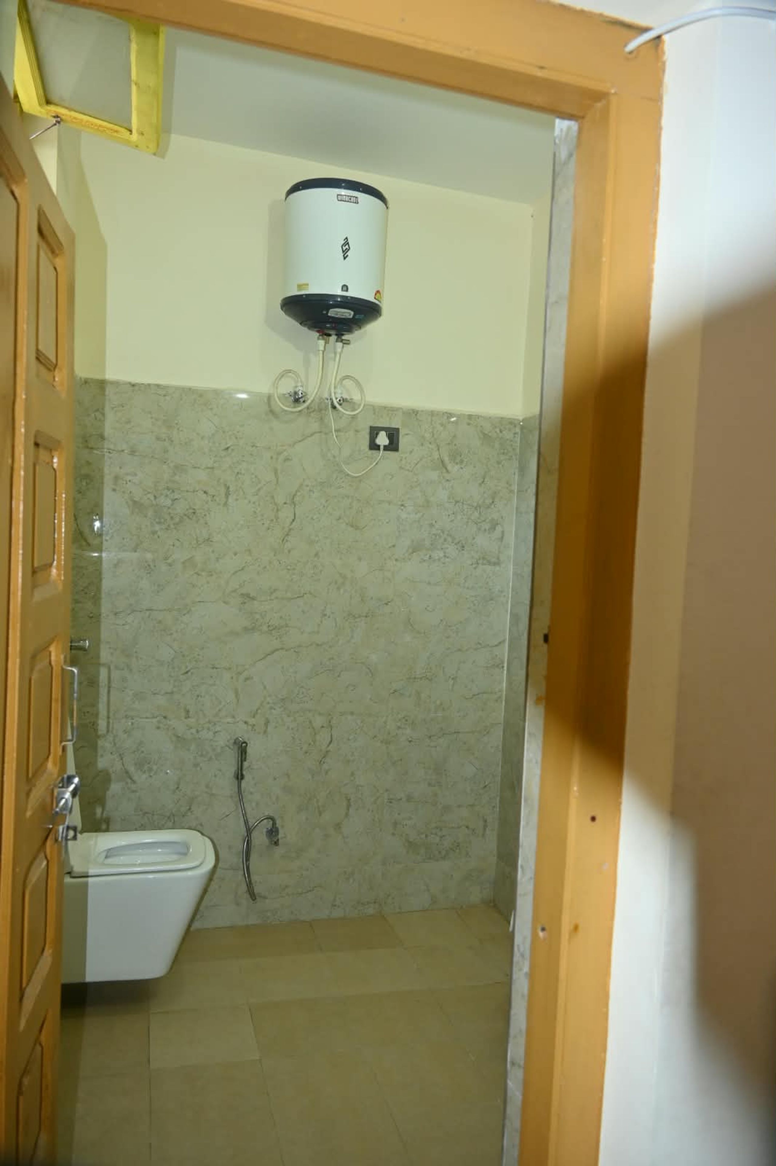 A bathroom with a toilet, a shower, and a water heater mounted on the wall.