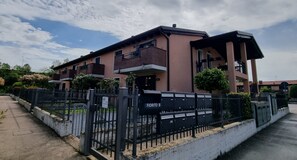 Un edificio residencial de varios pisos con fachada de ladrillo, entrada con portón y buzón identificado como 'FIORITO B'.