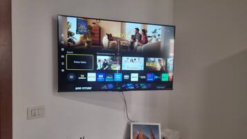 Una TV a schermo piatto montata a parete mostra l'interfaccia di un'app di streaming con diverse opzioni di contenuto.