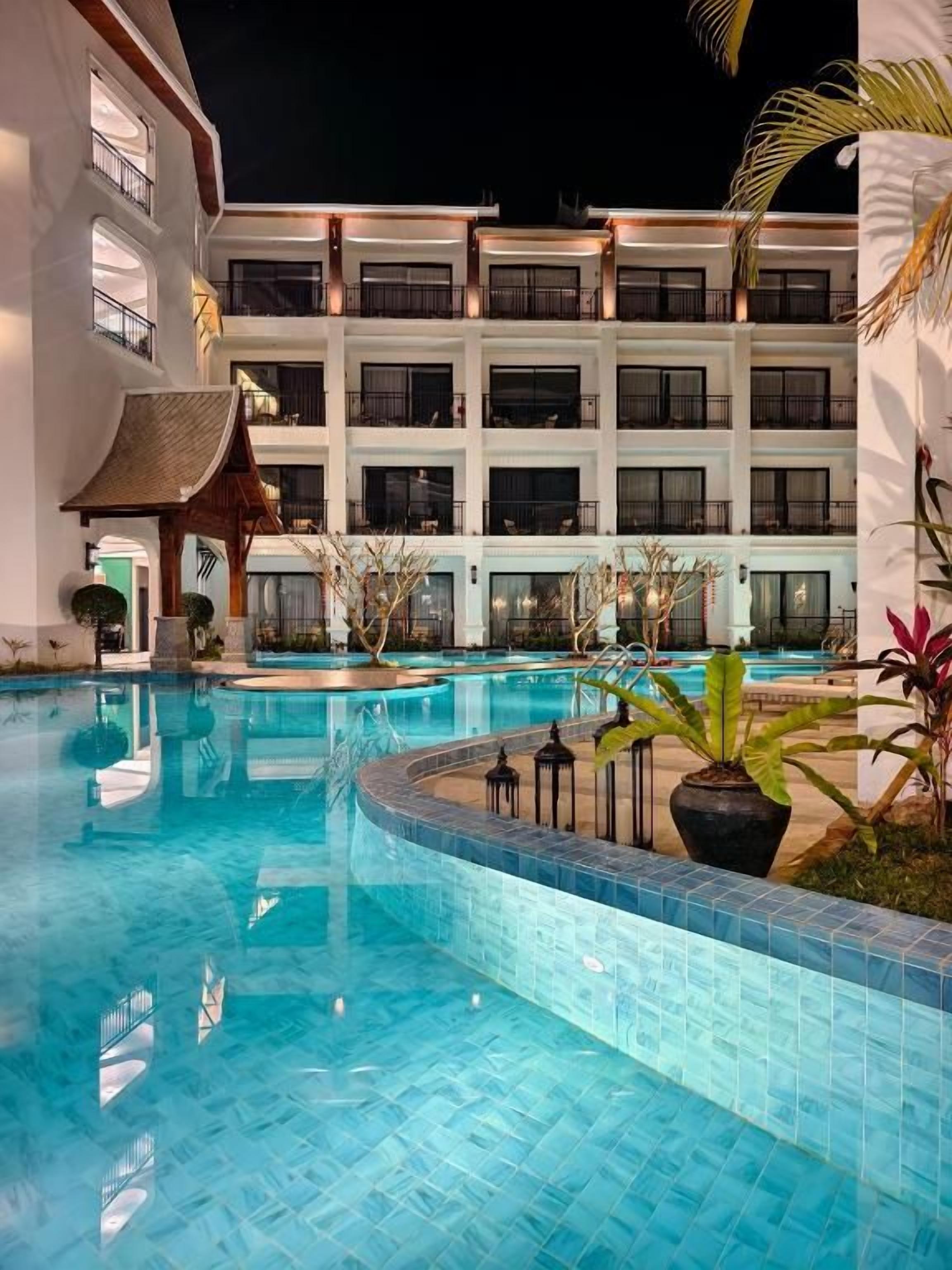 A hotel with a swimming pool, multiple balconies, and a traditional architectural style.