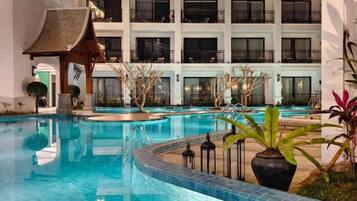 A hotel with a swimming pool, multiple balconies, and a traditional architectural style.