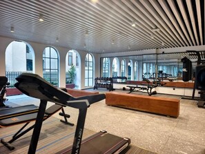 Un gimnasio con cintas de correr, bancos y equipo para levantamiento de pesas.