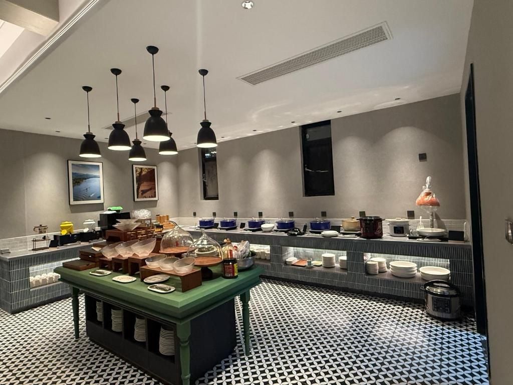 Een moderne keuken met een patroon vloer, een buffet met diverse gerechten en hanglampen.