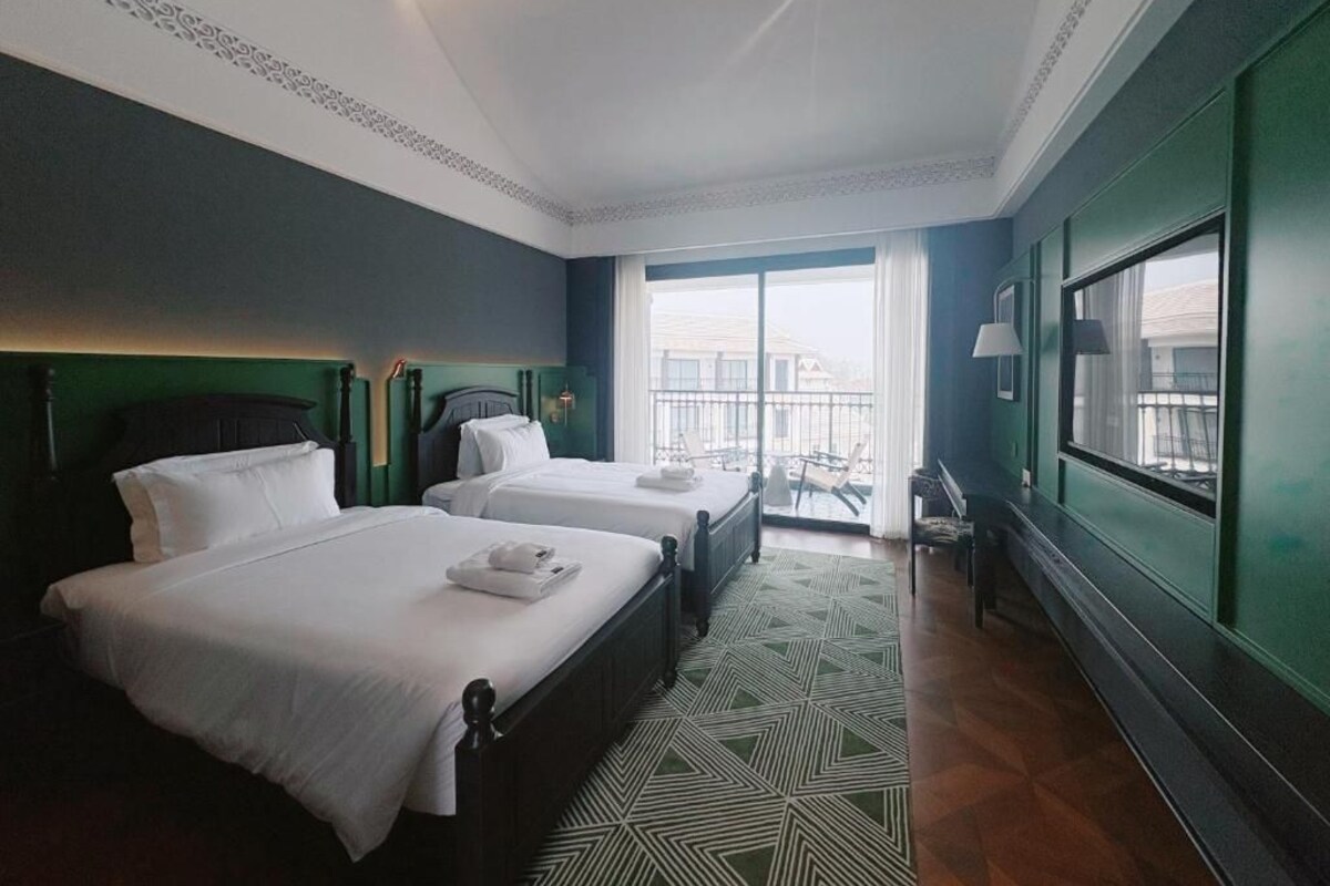 Una camera d'albergo con due letti, un balcone e vista sull'esterno.