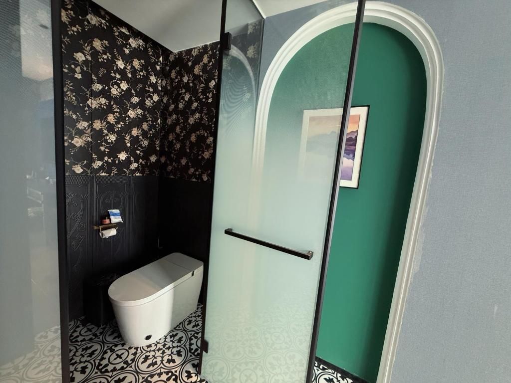 A bathroom with a toilet, a towel rack, and a shower area.