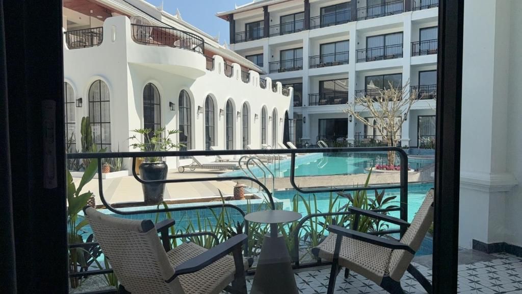 Un balcon d’hôtel avec une piscine, des chaises longues et une vue sur l’architecture du bâtiment.