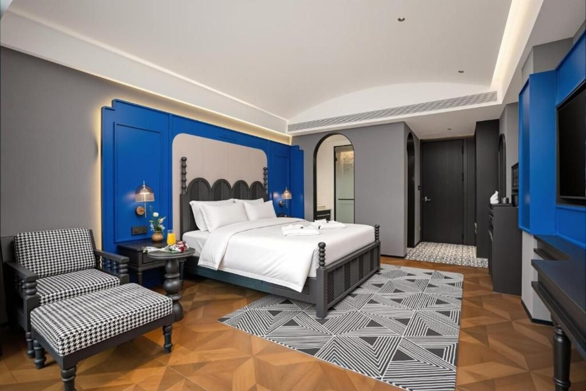 Una moderna camera d'albergo con un letto, un'area salotto e una televisione.