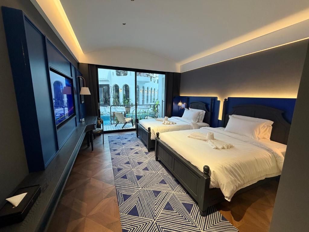 A hotel room with two beds, a large window, and a view of a building.