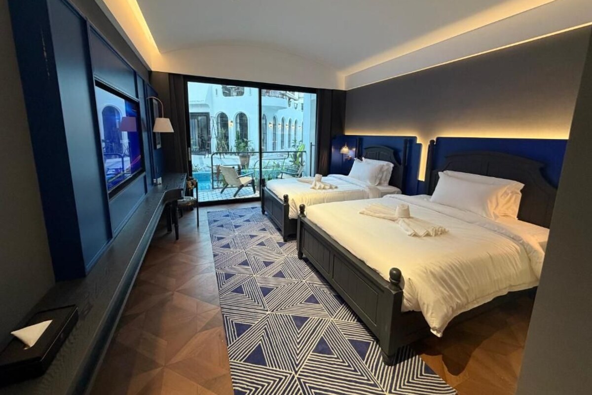 Una camera d'albergo con due letti, una grande finestra e vista su un edificio.