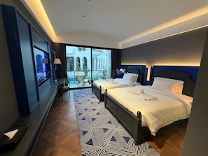 A hotel room with two beds, a large window, and a view of a building. - GLOND HOTEL (Luang Prabang)