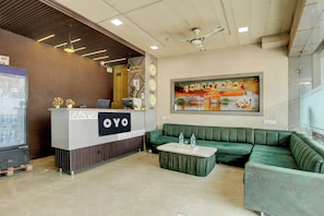 A reception area with a counter labeled 'OYO,' a green sofa, and a water dispenser. - Hotel O Avista Comfort (Amritsar)