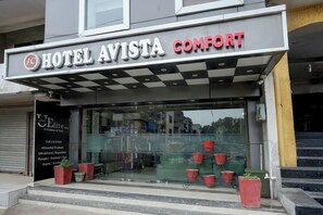 Ein Hotel Eingang mit Markisenstreifen und einem Schild, auf dem 'HOTEL AVISTA COMFORT' steht.