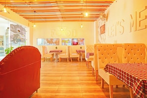 A restaurant interior with a wooden ceiling, tables with checkered tablecloths, and a wall with the text 'FAVORIT'. - Hotel O Teg Royal (Amritsar)