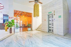 A hotel lobby with a marble floor, a ceiling fan, a staircase, and an elevator. - Hotel O Teg Royal (Amritsar)