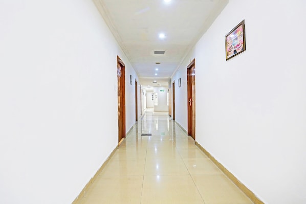 A long, narrow hallway with doors on both sides, leading to a room at the end. - Hotel O Teg Royal (Amritsar)