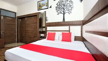 Habitación de hotel con cama, armario, espejo y un adorno en la pared.