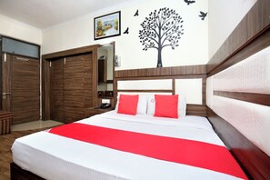 A hotel room with a bed, a wardrobe, a mirror, and a wall decoration. - Hotel O by OYO Ishita Residency (Amritsar)