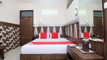A hotel room with a large bed, a wooden headboard, a bedside table, a mirror, and a tiled wall.