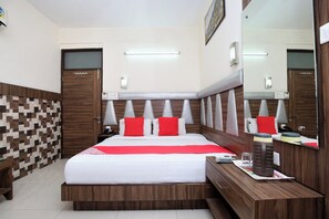 A hotel room with a large bed, a wooden headboard, a bedside table, a mirror, and a tiled wall. - Hotel O by OYO Ishita Residency (Amritsar)
