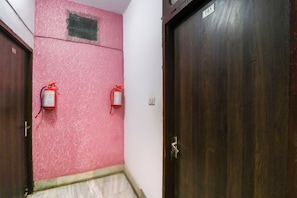 Ein Korridor mit rosafarbenen Wänden, zwei Holztüren und zwei an der Wand befestigten Feuerlöschern.