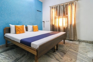 Una cama con estructura de madera, ropa de cama blanca y una colcha azul y morada.