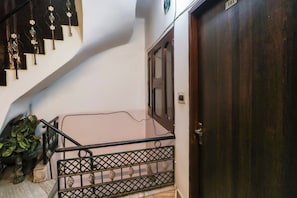 Eine Treppe mit Metallgeländer, einer Holztür und einem an der Wand befestigten Nummernschild.