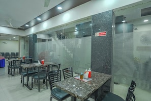A restaurant with marble tables and chairs, a 'No Smoking' sign, and a glass partition. - Hotel O Shree Vishnu Residency (Amritsar)