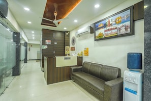 A reception area with a reception desk, a sofa, a water dispenser, and a wall-mounted air conditioner. - Hotel O Shree Vishnu Residency (Amritsar)