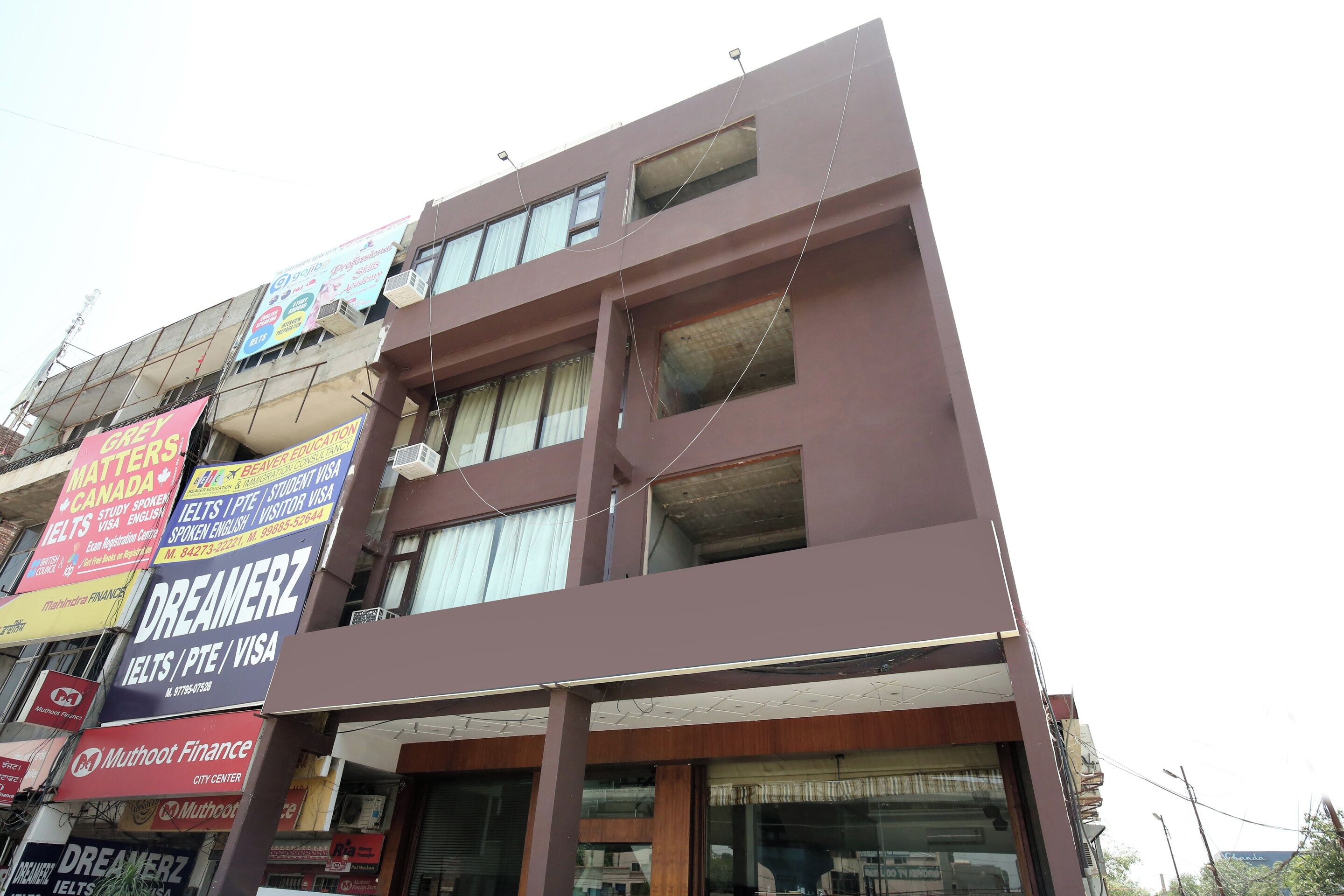 Um edifício de vários andares com diversos anúncios comerciais, incluindo um para serviços Dreamerz IELTS/PTE/VISA.