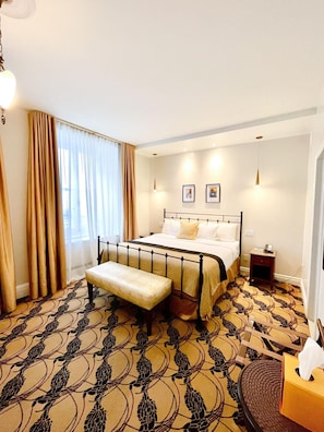 Une chambre d’hôtel comprenant un lit, un banc, une table de chevet et une petite table avec une boîte de mouchoirs.