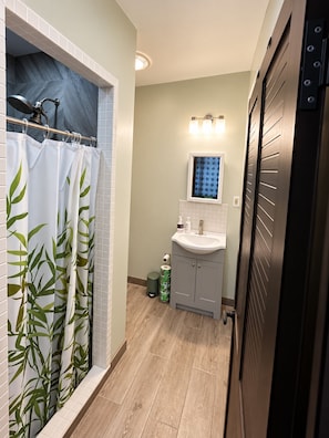 A bathroom with a shower curtain, a sink, and a toilet. - Le 'Ali Retreat - Small space, Big Comfort (Tafuna)