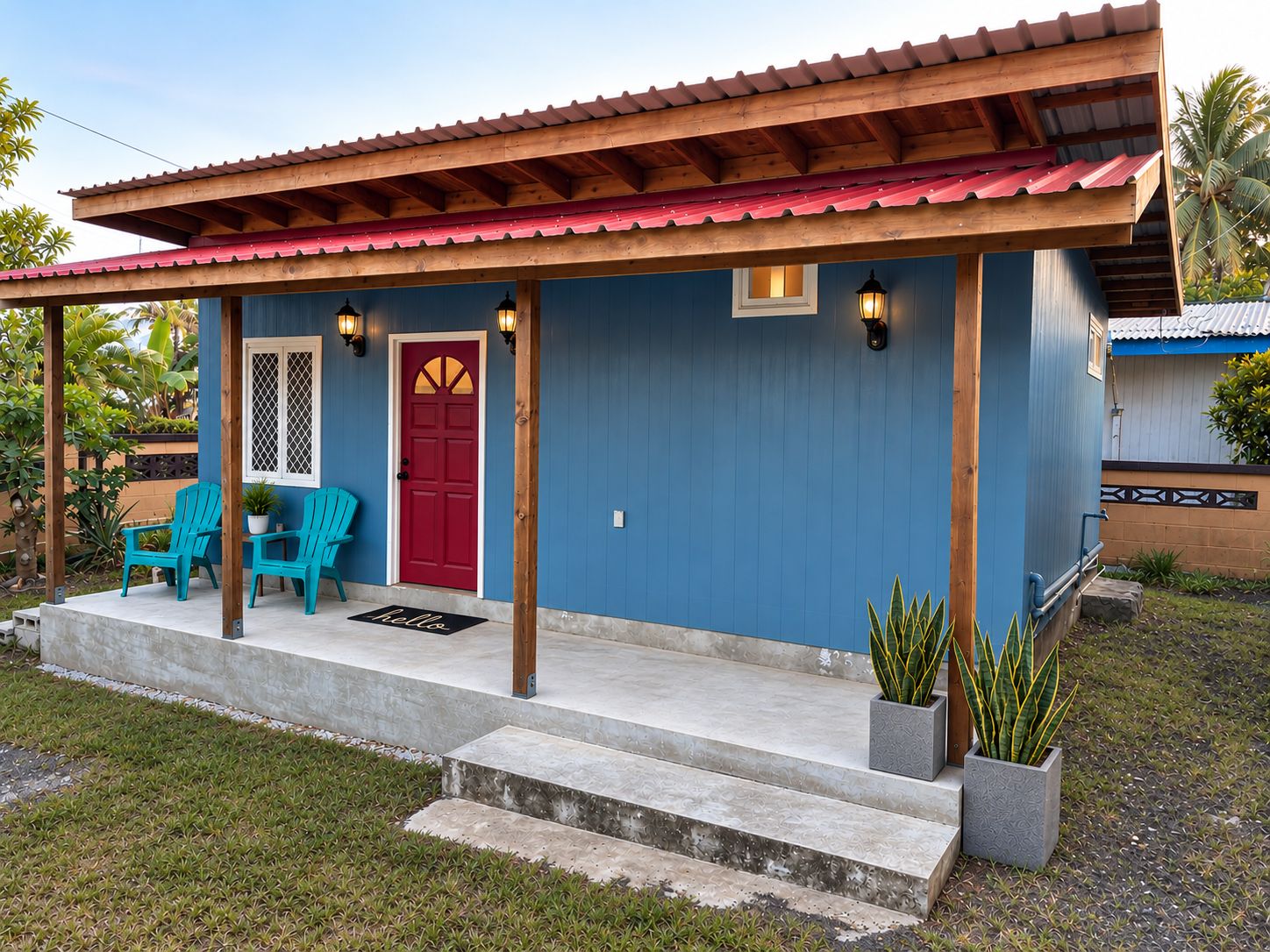 Een huis met een rode deur, blauwe muren en een veranda met twee stoelen en een deurmat.
