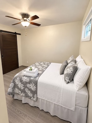 A bedroom with a bed, a ceiling fan, and a sliding door. - Le 'Ali Retreat - Small space, Big Comfort (Tafuna)