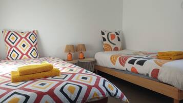 A hotel room with two beds, each with patterned bedding, a pair of lamps, and a pair of towels on the bed.