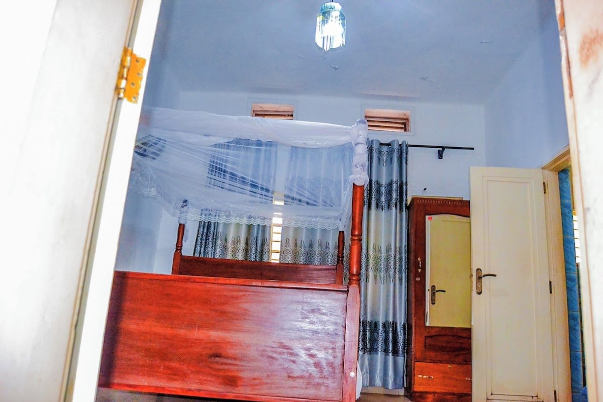 Un pasillo estrecho con una cama de madera, una puerta y una ventana con cortinas.