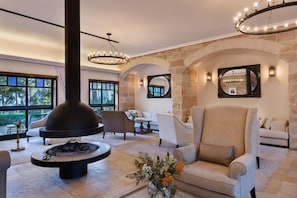 Amplia sala de estar con pared de piedra, chimenea y asientos cómodos.