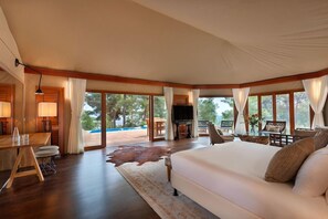 Un dormitorio amplio con una cama grande, televisión y zona de comedor con vistas al exterior.