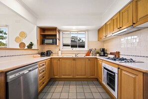 Eine moderne Küche mit Holzschränken, einem Geschirrspüler, einem Herd und einem Fenster.