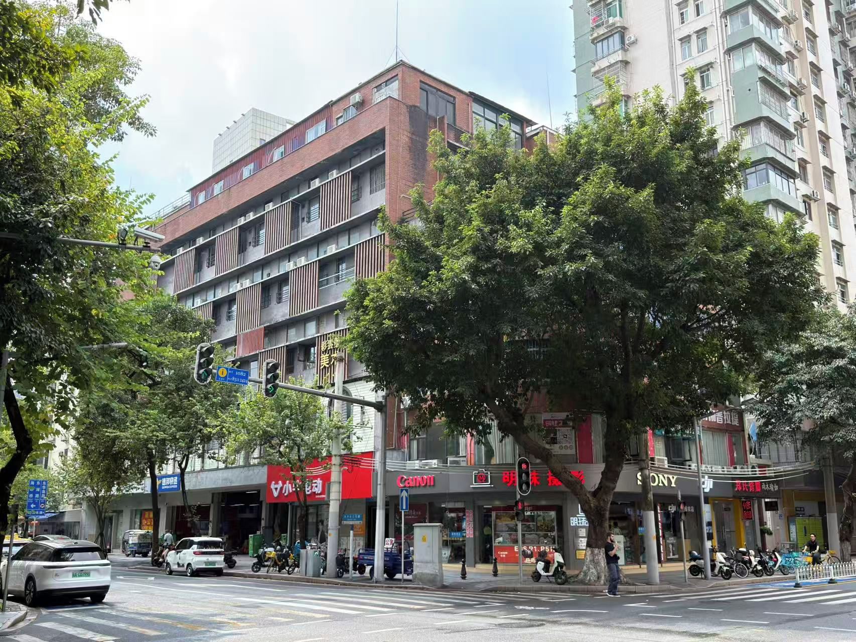 A multi-story building with commercial establishments on the ground floor, including a Canon store.