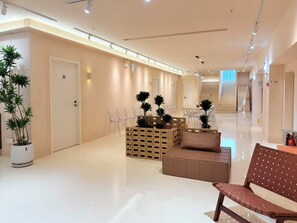 A modern hotel lobby with a reception desk, seating area, and a staircase. - Sunrise Voyage (Guangzhou)