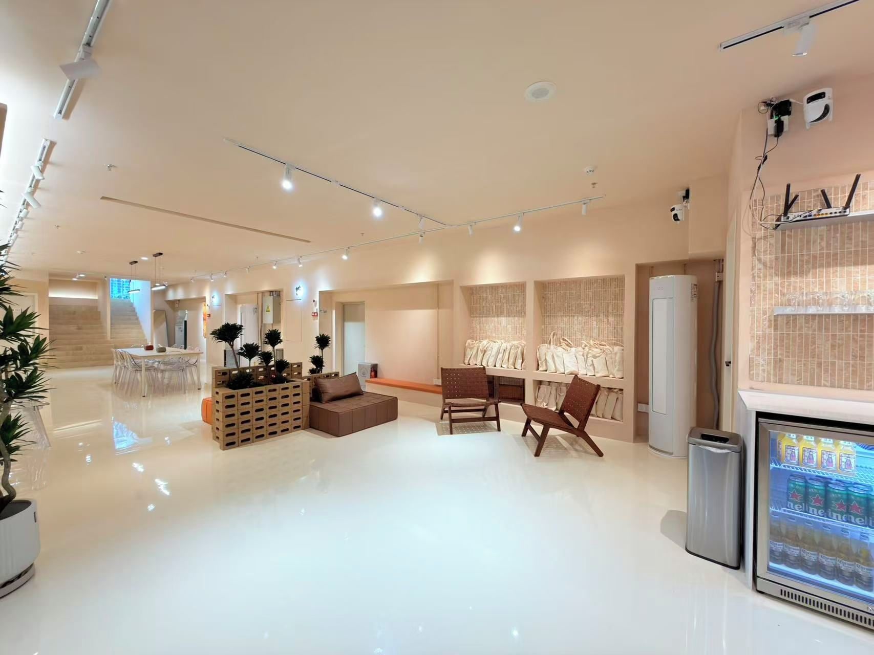 A spacious, modern interior with a central seating area, a refrigerator stocked with beverages, and a clear view of the adjacent room.