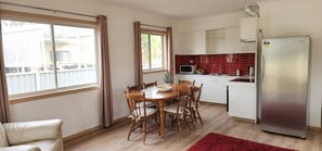A compact kitchen with a dining table, chairs, a refrigerator, and a microwave.