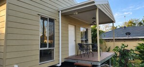 A covered patio with a table and chairs, a window, and a door.