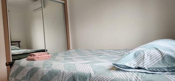 A bedroom with a bed, a mirror, and a wardrobe.