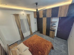 Un dormitorio con cama, armario y ventilador de techo.