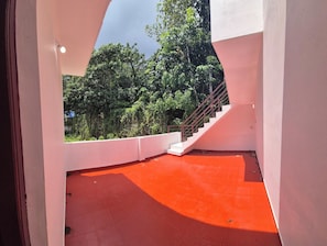 Diseño arquitectónico moderno con piso rojo, una escalera y vista a vegetación exuberante.