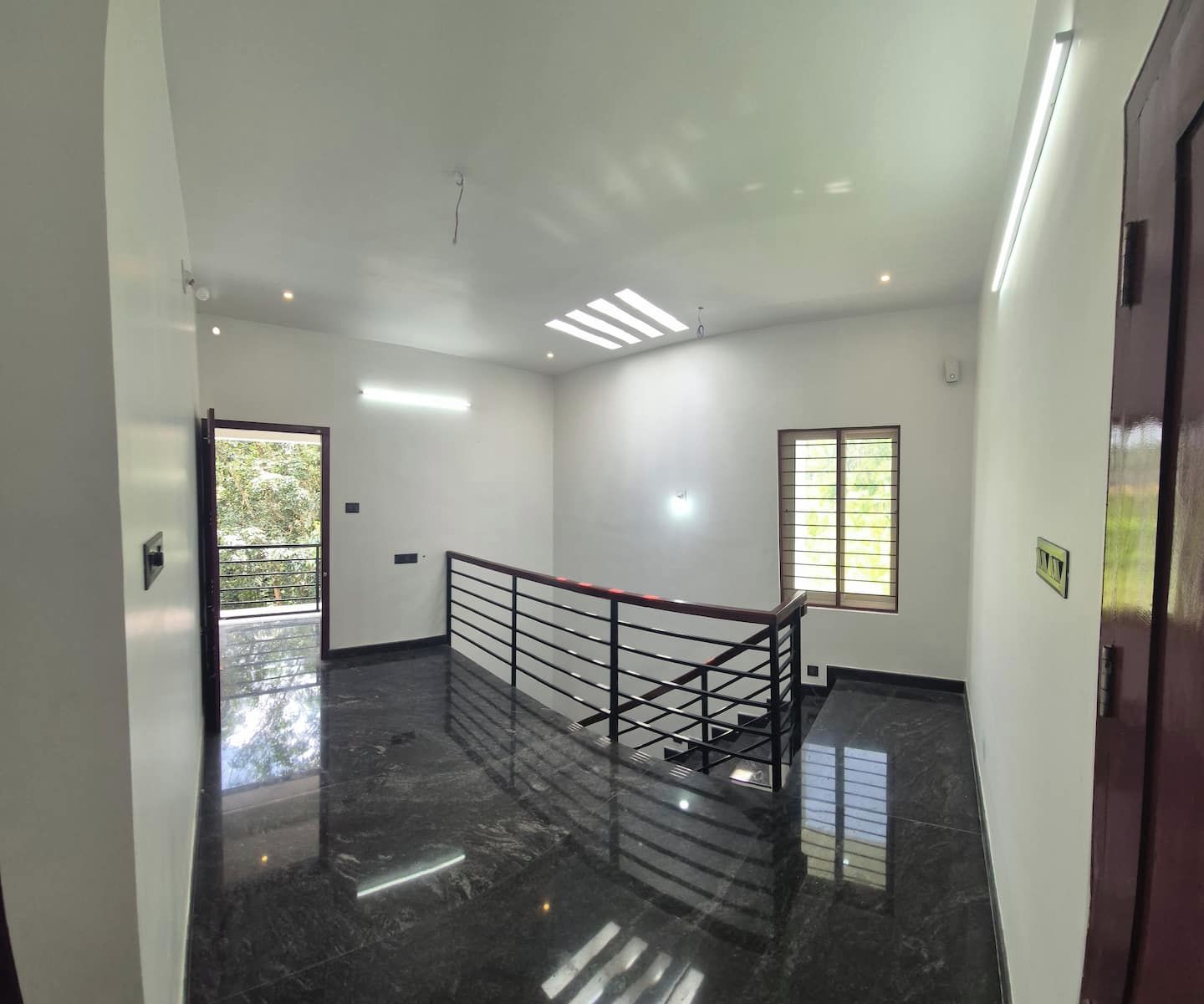 Un interior limpio y moderno con piso de mármol, una escalera con barandilla de metal y una puerta con ventanal.